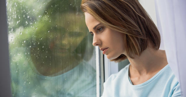 Young Woman With Head Against Window Thinking