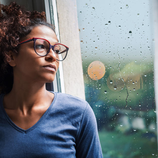Woman Looking Out Of Window Worried